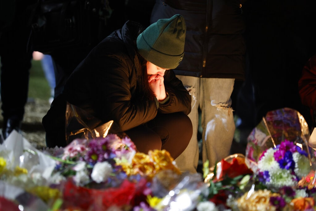 Catie Henkelman, 21, a Michigan State senior, takes a moment after lighting a candle as mourners attend a vigil at The Rock on the grounds of Michigan State University in East Lansing, Mich., Wednesday, Feb. 15, 2023.