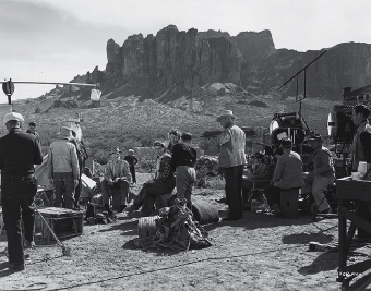 Behind the camera on location in the Arizona desert filming Universal's comedy Lady in a Jam (1942) is seen Irene Dunne (sitting, center) dressed for a scene in the film.