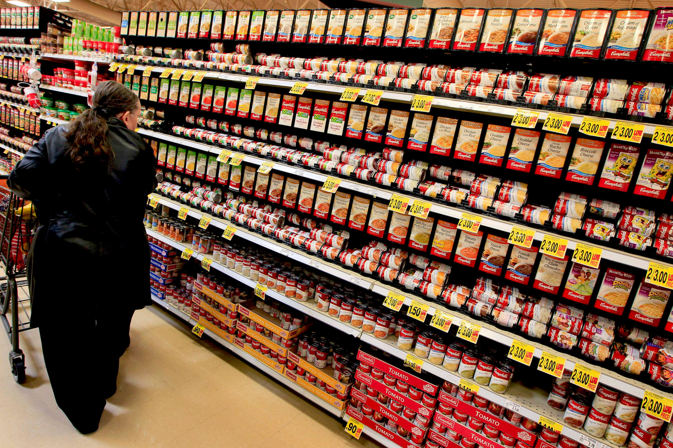 image of woman shopping in the soup aisle of groccery store