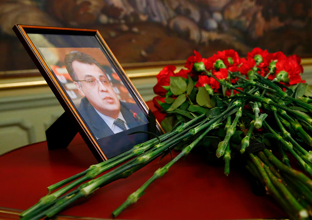 Image of casket, flowers and a picture of Karlov