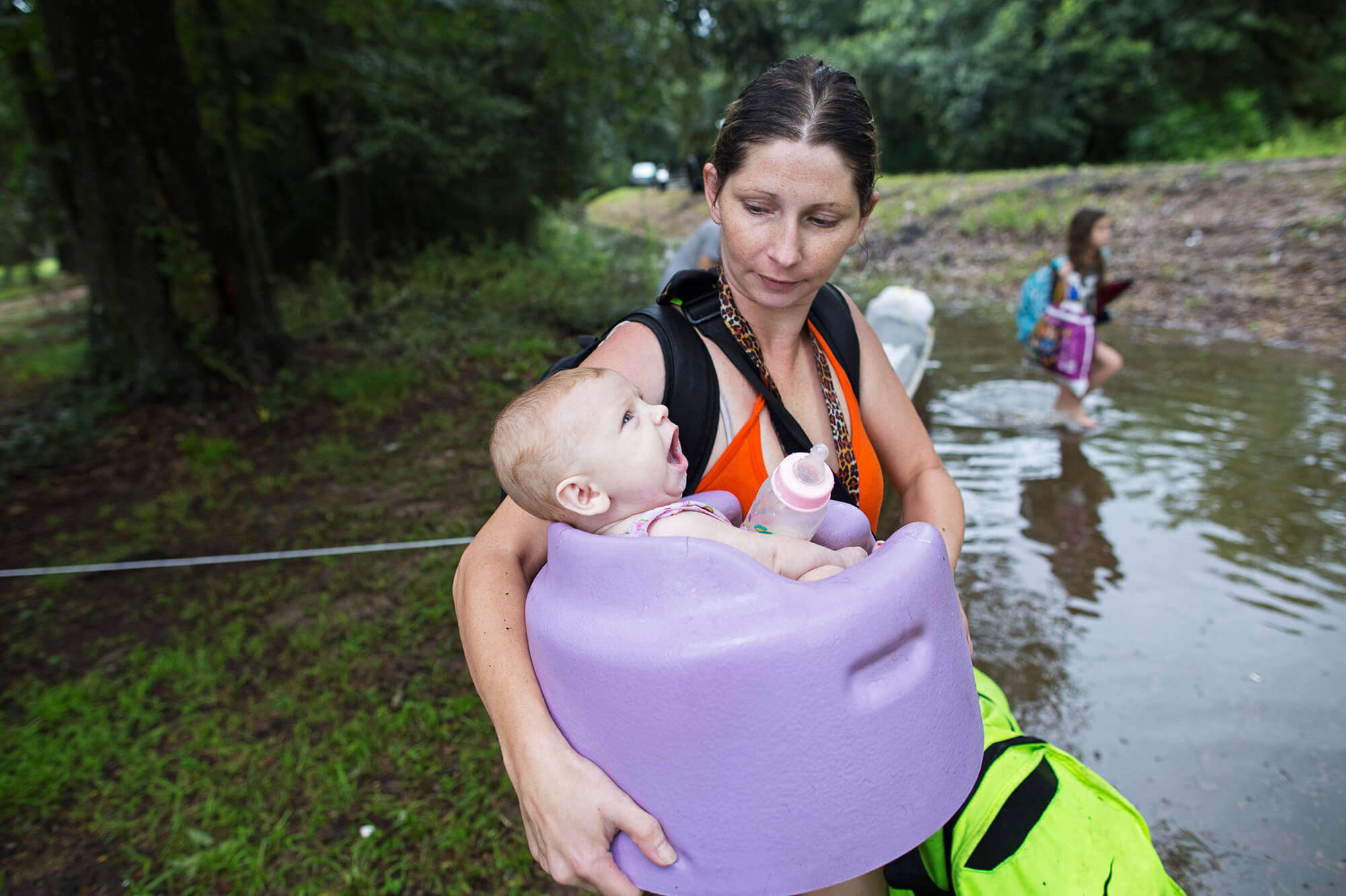 Image of mother carrying child through the flood in Louisiana