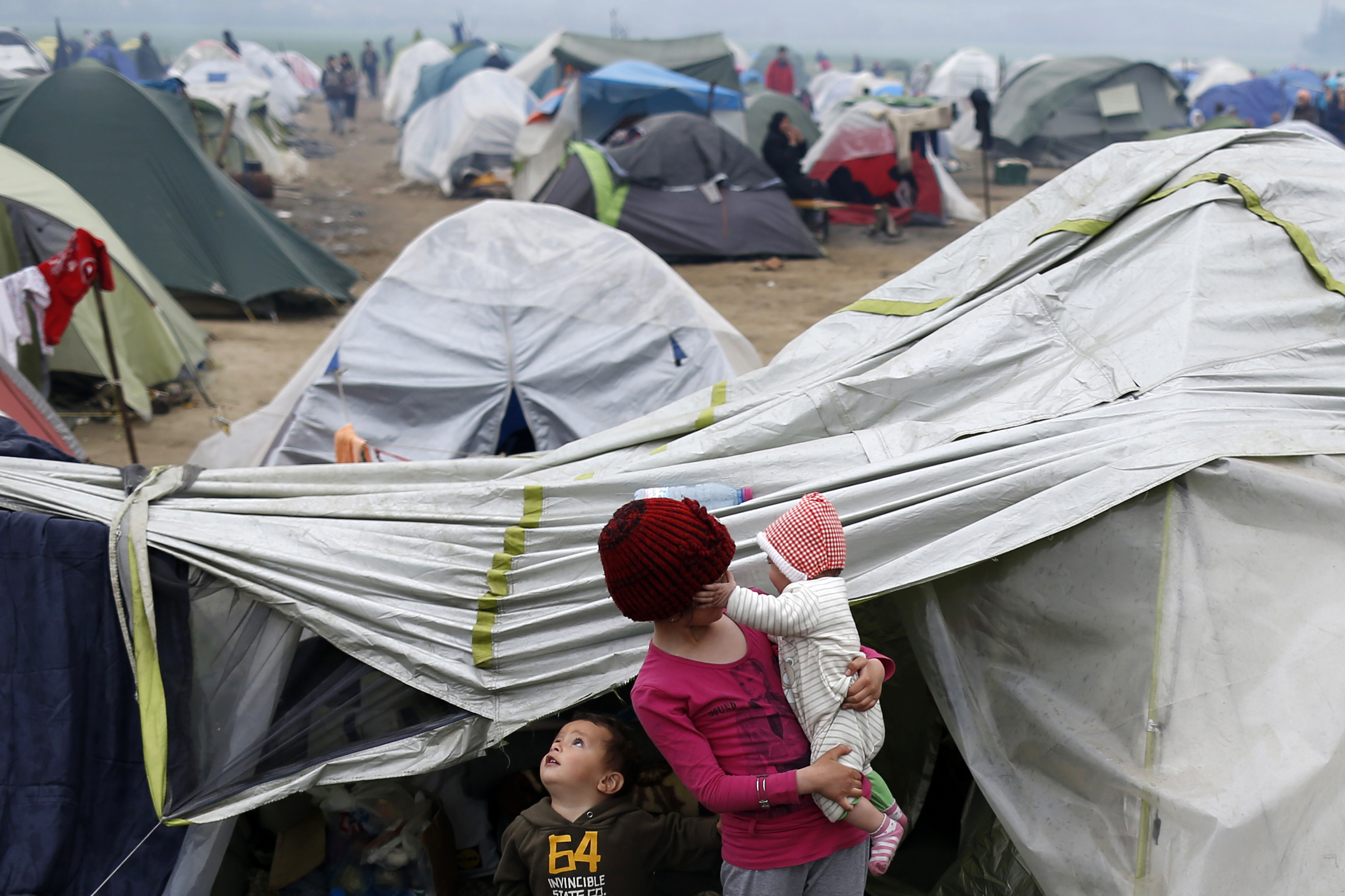 Migrant children stand in front of tents in the makeshift refugee camp at the northern Greek border point of Idomeni, Greece