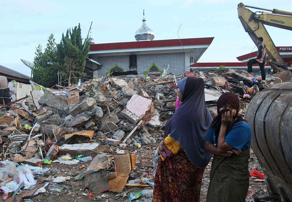 Image of two women next to destroyed building