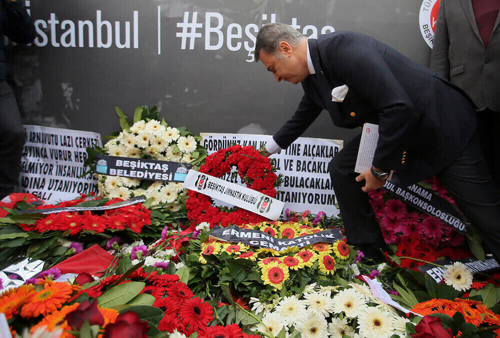 Image of man placing wreath onto memorial for those killed
