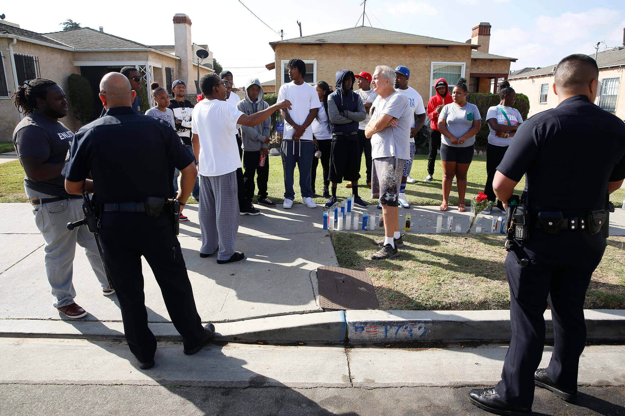 Image of police officers and neighbors around a makeshift memorial