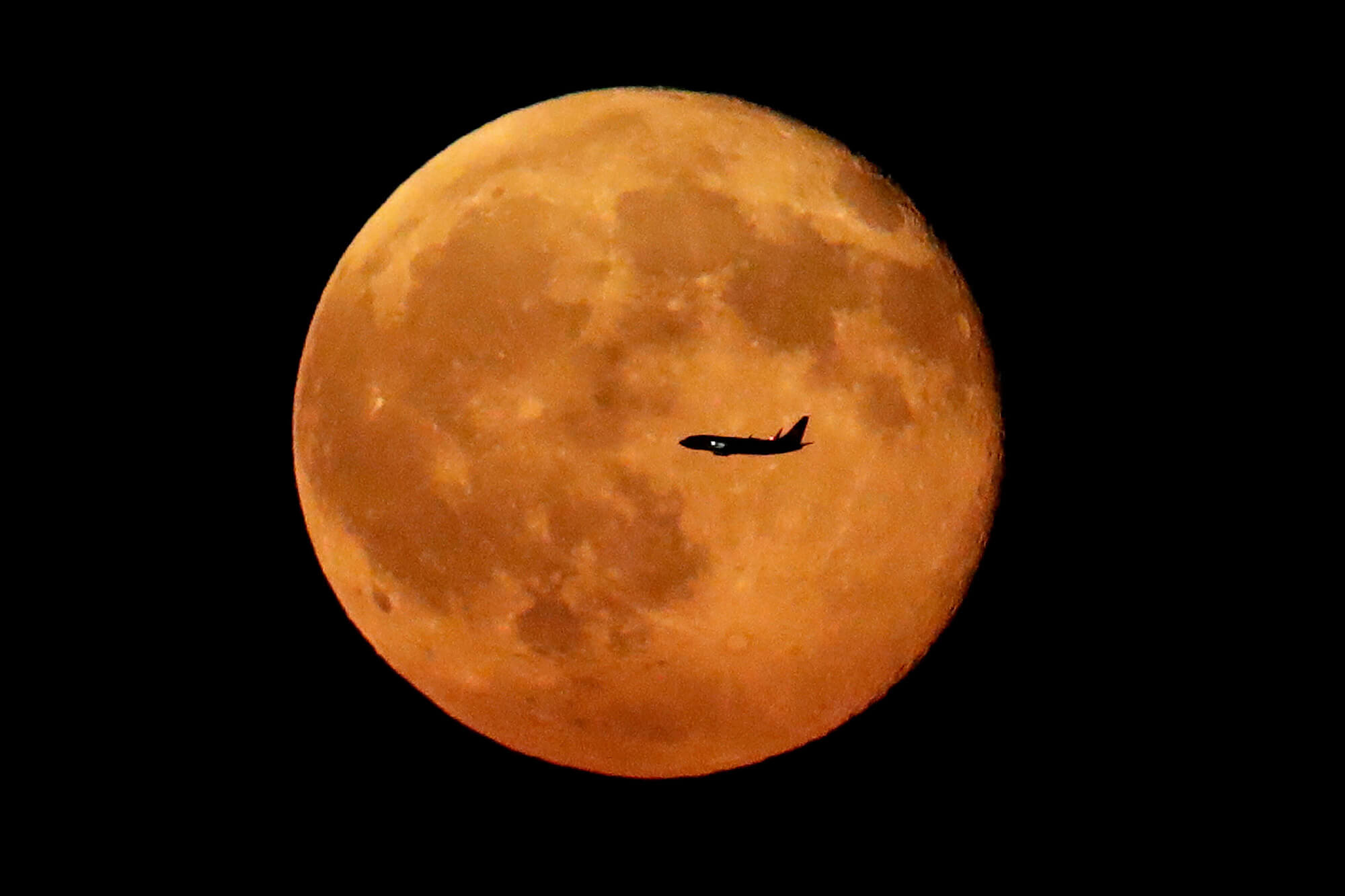 Image of the moon with plane in front of it.