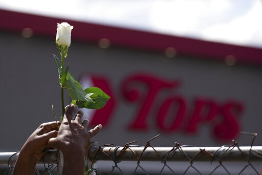Woman holds a flower in front of Tops Friendly Market