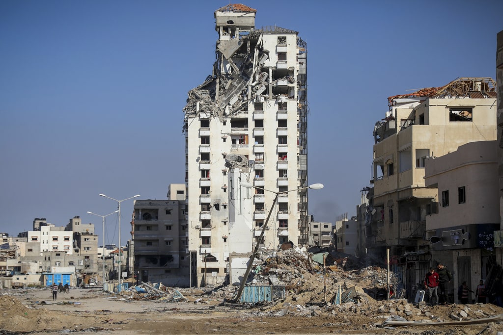 Palestinians walk by destroyed buildings in Gaza City on Wednesday, Nov. 29, 2023, the sixth day of the temporary ceasefire between Hamas and Israel.