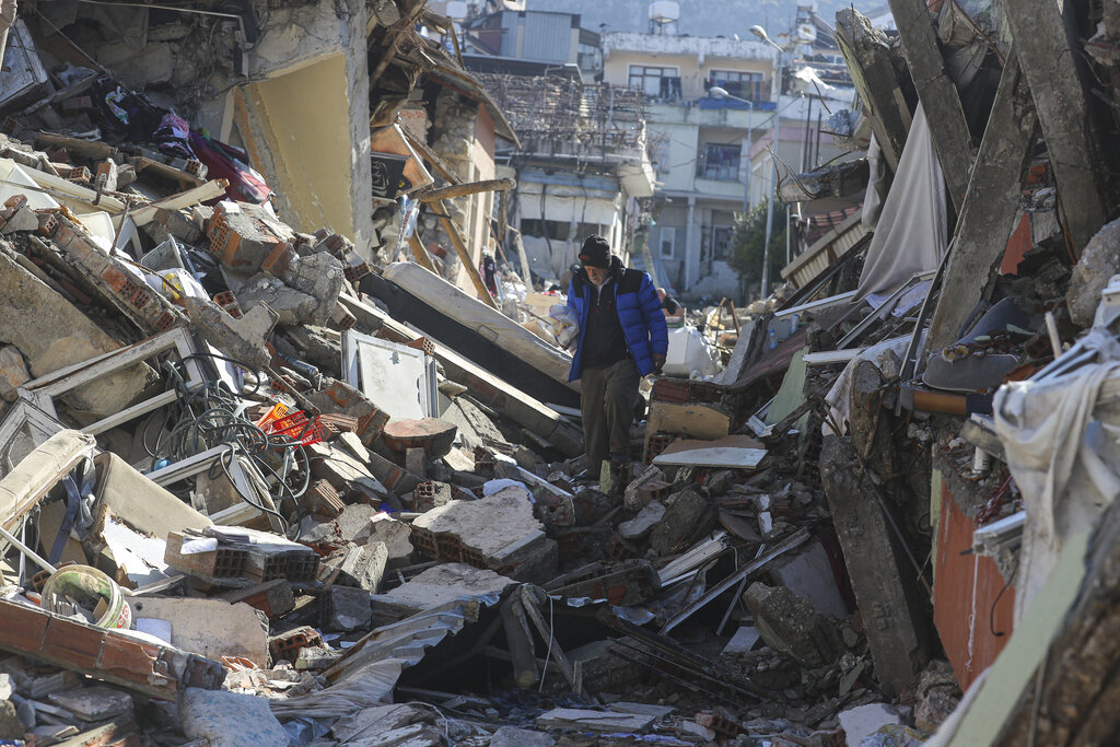 A man walks among the debris of collapsed buildings in Hatay, southern Turkey, Thursday, Feb. 9, 2023. Emergency crews made a series of dramatic rescues in Turkey on Friday, pulling several people, some almost unscathed, from the rubble, four days after a catastrophic earthquake killed more than 20,000.